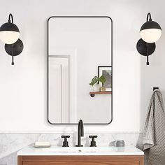 a bathroom vanity with two lights and a mirror on the wall above it is shown