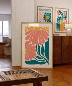 three framed art pieces on the wall in a room with wood floors and wooden furniture