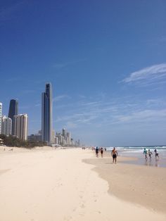 people walking on the beach in front of tall buildings