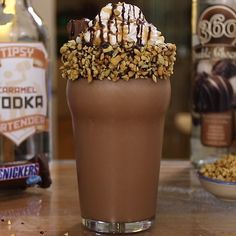 chocolate milkshake with whipped cream and nuts on top, surrounded by liquor bottles