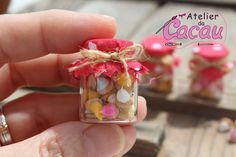 a person holding a tiny glass jar filled with candies and marshmallows