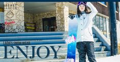 a woman holding a snowboard standing in front of a building