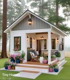 a small white house with green shutters and flowers on the front steps, surrounded by trees