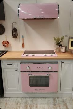 a pink stove top oven sitting inside of a kitchen next to a wooden countertop