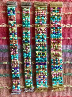 three beaded bracelets sitting on top of a pink and green table cloth next to each other