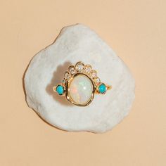 A refreshed and modern take on the ring that started it all - Jillian's reworked heirloom from her grandmother. An Australian opal is complemented by a white diamond headdress and two turquoise on either side. The abstract bezel adds a modern, unique touch - a fun statement ring for any fine jewelry collection. Heirloom Multi-stone Diamond Opal Ring, Heirloom Multi-stone Opal Diamond Ring, Heirloom 14k Gold Opal Ring With Accent Stones, Australian Opal Ring, Bezel Ring, Diamonds And Gold, Fine Jewelry Collection, Australian Opal, Opal Rings