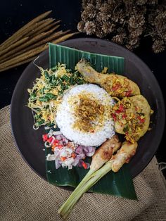 a black plate topped with rice and meat next to other foods on top of a table