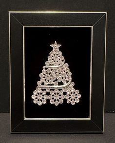 a christmas tree made out of crystal beads in a black frame with a star on top