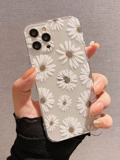 a woman holding up her phone case with white flowers on the front and back cover