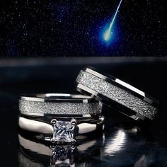 two wedding bands with a diamond in the middle and an object in the background that looks like a shooting star