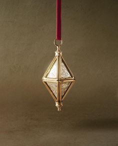 a gold ornament hanging from a red ribbon