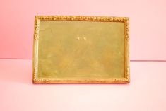 a gold framed painting on a pink background