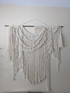 a white wall hanging with macrami and tassels on it's sides