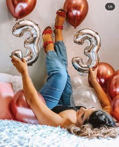 a woman laying on top of a bed with balloons in the shape of two numbers