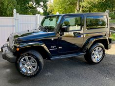 a black jeep parked in front of a white fence