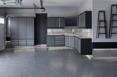 an empty garage with gray cabinets and ladders