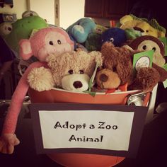 there is a basket full of stuffed animals with a sign that says adopt a zoo animal