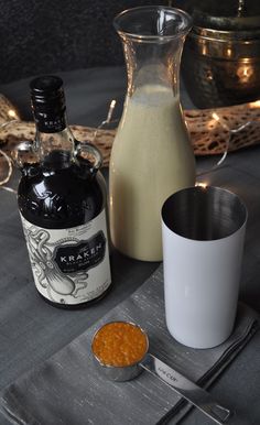 a table topped with bottles of booze next to a bowl of beans and a cup