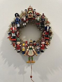 a christmas wreath hanging on the wall with many ornaments around it and a small figurine