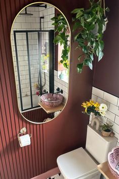 a white toilet sitting next to a bathroom sink under a round mirror on a wall