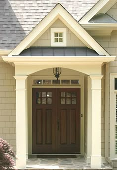 the front entrance to a house with two double doors and brick walkway leading up to it