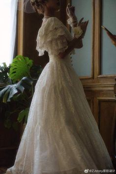 a woman in a white dress and hat standing next to a mirror with a bird on it