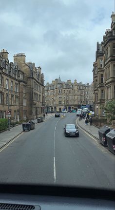 cars are driving down the street in front of some tall buildings on a cloudy day