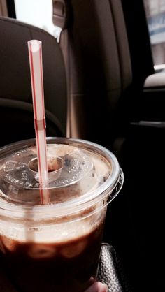 a person holding a drink in their hand while sitting in the back seat of a car