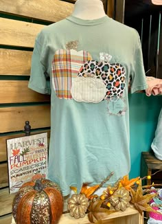 a t - shirt with an animal patch on it sitting next to some pumpkins