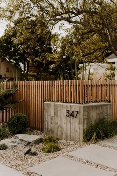 a cement planter sitting in front of a wooden fence with the number 547 written on it