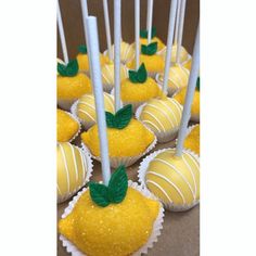 cake pops with yellow frosting and green leaves on them are arranged to look like lemons