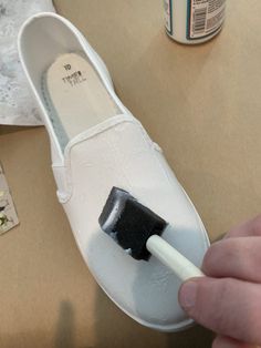 a person is painting a pair of white shoes with a black paintbrush on it