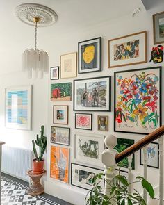 there are many pictures on the wall above the stairs in this house with plants and potted cacti