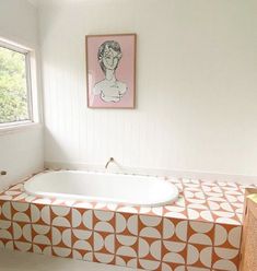 an orange and white bathtub in a bathroom next to a painting on the wall