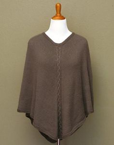 a woman's brown sweater on a mannequin head stand against a wall