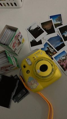 a yellow camera sitting on top of a table next to pictures and other things around it