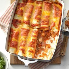 a casserole dish with meat, cheese and sauce in it on a cutting board