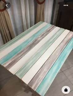 a table made out of wooden boards sitting on top of a tile floor next to a window