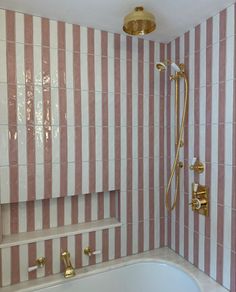 a bathroom with pink and white striped wallpaper, gold fixtures and a bathtub