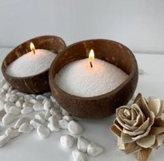 two candles sitting on top of white rocks next to a flower