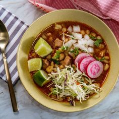 a bowl of soup with beans, radishes, and shredded cheese on the side