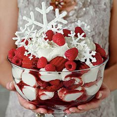 a person holding a large bowl filled with fruit and ice cream covered in snow flakes