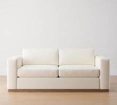 a white couch sitting on top of a hard wood floor next to a white wall