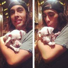 a man holding two puppies in his arms and smiling at the camera while wearing a baseball cap