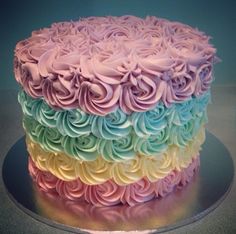 a multi - colored cake with frosting flowers on top is shown in this image