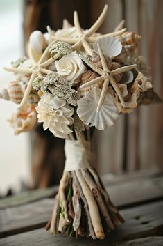 a bridal bouquet with seashells and starfish on the stems is sitting on a wooden table