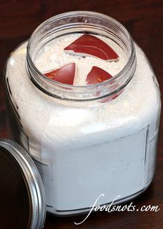 a glass jar filled with white and red liquid sitting on top of a wooden table