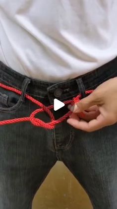 a person is pulling on some red rope with their hands while standing in front of a white t - shirt