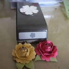 two paper flowers sitting on top of a table next to an open cell phone case