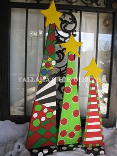 three colorful christmas trees sitting in front of a door